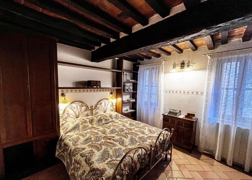 a bedroom with a bed in a room with windows at Dimora del Campanile in Torrita di Siena