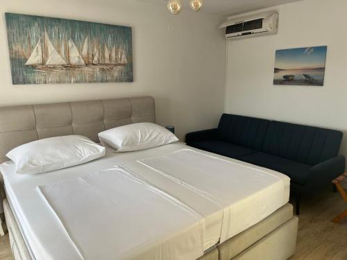 a bedroom with a white bed and a couch at Roso Seafront House in Selca kod Bogomolja