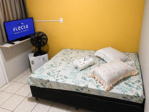 a bed with pillows and a tv in a room at Quarto em Matinhos | Viva o Melhor do Litoral in Matinhos
