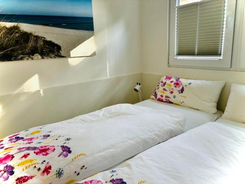 a bedroom with two beds and a window with a painting at Tiny House Boddenblick in Groß Kordshagen
