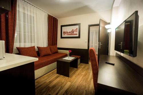 a hotel room with a couch and a flat screen tv at Penzión Talisman in Rajecké Teplice