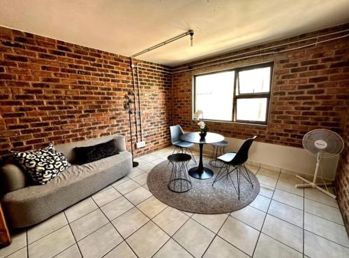 a living room with a couch and a brick wall at Tulisa Park in Johannesburg
