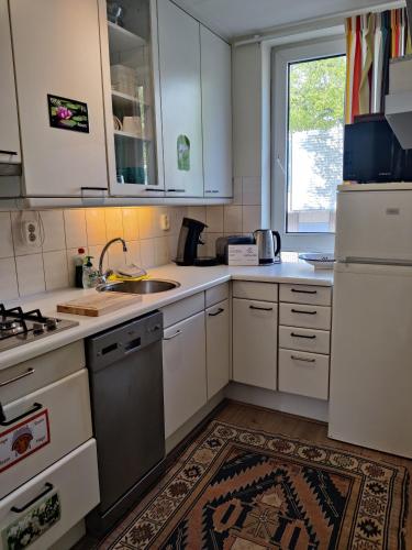 a kitchen with white cabinets and a sink and a window at City Center Rooms with Shared Facilities by UMCG in Groningen