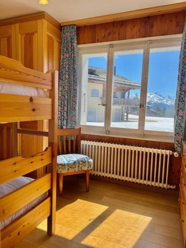 a bedroom with a bunk bed and a window at Chalet Le Nid D'argent - Dans la nature in Crans-Montana