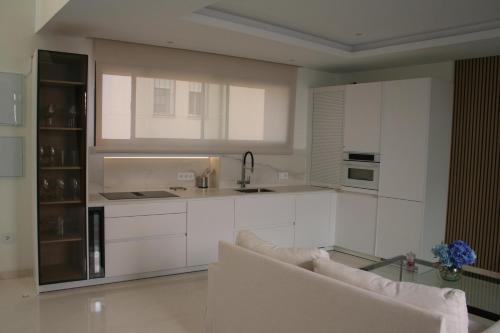 a white kitchen with a couch and a sink at Casa Rural La Tajuela in Bohonal de Ibor