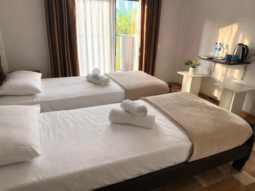two beds with towels on them in a hotel room at Salo Pool Hotel by the Sea in Gonio