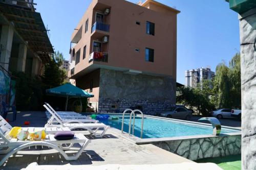 a swimming pool with lounge chairs and a building at Salo Pool Hotel by the Sea in Gonio