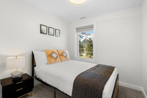 a white bedroom with a bed and a window at Golden Ridge Collection in Canmore