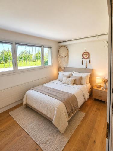 a bedroom with a large bed and two windows at Stylish house with garden, sauna & pool in Mörschwil