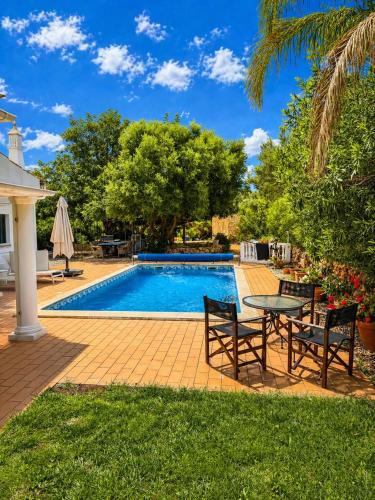 a patio with a table and chairs next to a pool at Farm of Dreams Algarve in Almancil