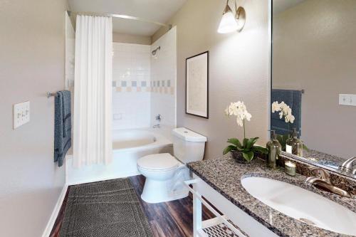 a bathroom with a toilet and a sink and a tub at King Aqua Suite Walkable Legacy West King Bed, Pool & Gym in Plano