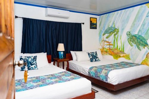 two beds in a room with a painting on the wall at Olas Permanentes El Zonte in El Zonte