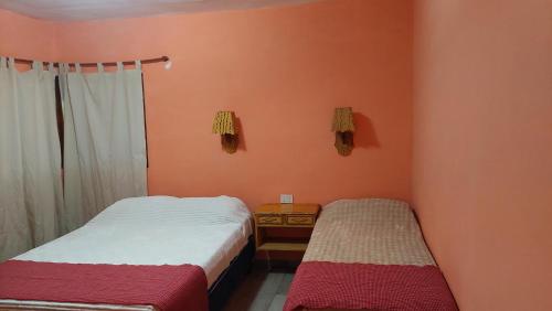 two beds in a room with orange walls at Tinkunaco in Purmamarca