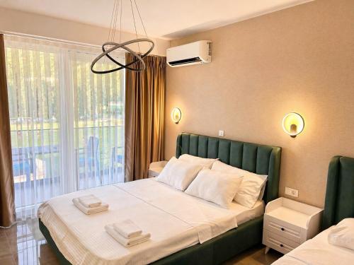 a bedroom with a bed with a green headboard and a window at Lungolago Apartment Ohrid in Ohrid