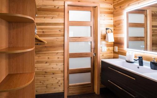 a bathroom with a sink and a wooden wall at Sunrise Valley Suite in West Kelowna