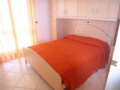 - une chambre avec un lit et une couverture orange dans l'établissement Zancan Appartament, à Grado