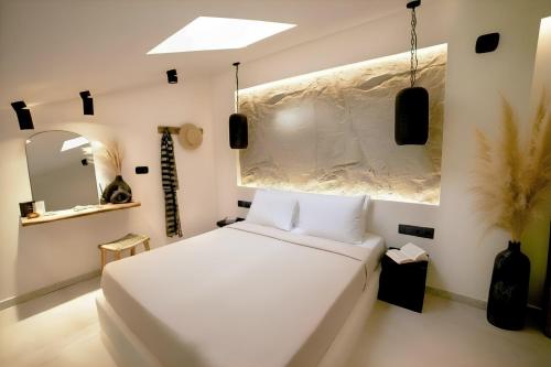 a white bedroom with a white bed and a mirror at ŌMNIMI Signature Living in Skala Potamias