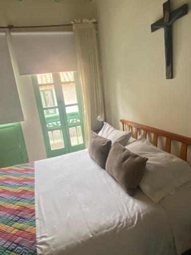 a bed with white sheets and a cross on the wall at Apartamento Turístico Frailejones in Duitama
