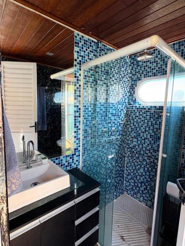 a bathroom with a sink and a shower with blue tiles at House Boat in Capitólio