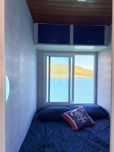 a bed in a small room with a window at House Boat in Capitólio