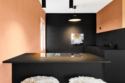 a kitchen with a black counter with two white stools at Casa Formentera in Molde
