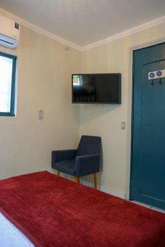 a room with a chair and a television on a wall at Hostel Castell Di Madre in Santos