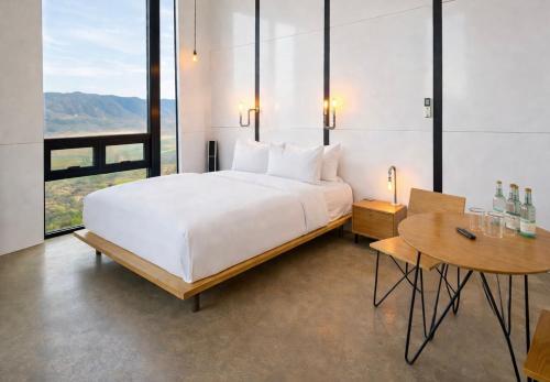 a bedroom with a large white bed and a table at Encuentro Guadalupe in Valle de Guadalupe