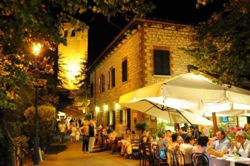 grupa ludzi siedzących przy stołach przed budynkiem w obiekcie Osteria Belvedere w mieście San Leo