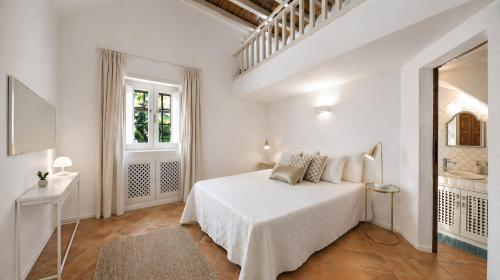 a white bedroom with a bed and a window at Porto Cervo Sea and Nature Villa in Porto Cervo