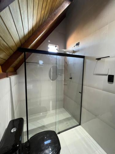 a glass shower in a bathroom with a black chair at Chalés Pôr do Sol in Mucugê