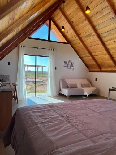 a bedroom with a large bed and a large window at Chalés Pôr do Sol in Mucugê