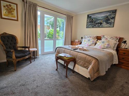 a bedroom with a bed and a chair and a window at Geyser Lookout BnB in Rotorua