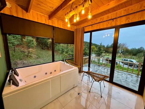 a large bathroom with a large tub and windows at Alpine Cabins Gjinar in Gjinar