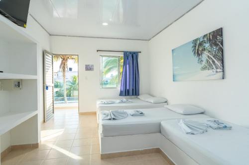 a white room with two beds and a window at Blue Apartahotel Coveñas in Coveñas