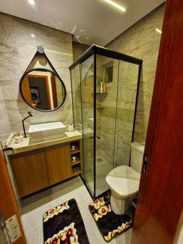 a bathroom with a toilet and a sink and a mirror at Apartamento Confortável in Ananindeua