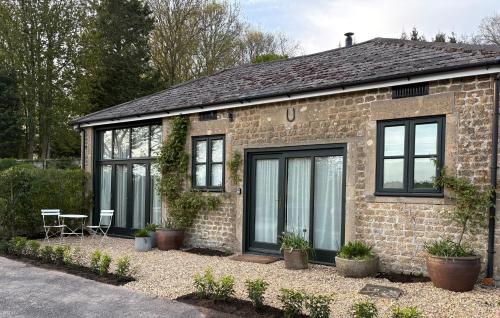a brick house with black windows and plants at The Stables in Corsley
