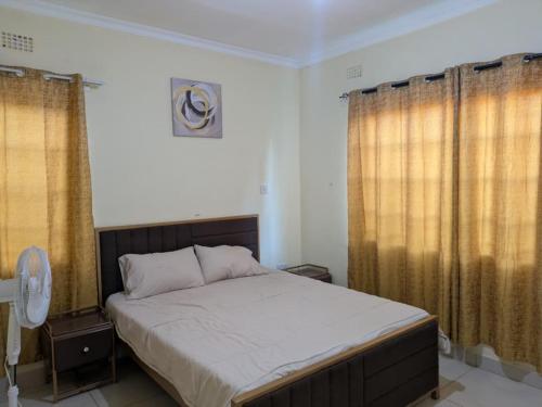 a bedroom with a large bed with curtains and a fan at Rehoboth Area 49 Guest House in Lilongwe