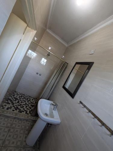 a white bathroom with a sink and a shower at Rehoboth Area 49 Guest House in Lilongwe