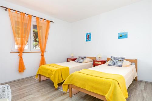 a bedroom with two beds with yellow sheets and a window at Apartments by the sea Maslinica, Solta - 14748 in Maslinica