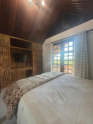 a bedroom with a large bed and a window at Chalé Suiço Bananeiras in Bananeiras