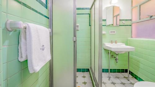 a green bathroom with a sink and a mirror at Hotel Mariscal in Mexico City