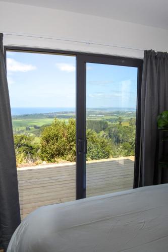 a bedroom with a large window with a view at Tūhua View Retreat in Waihi Beach