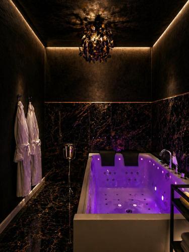 a bathroom with a purple bath tub with a chandelier at Love Room- Adult Only in Bucharest