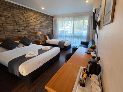 a hotel room with two beds and a brick wall at Homestead Motor Inn & Apartments in Bendigo