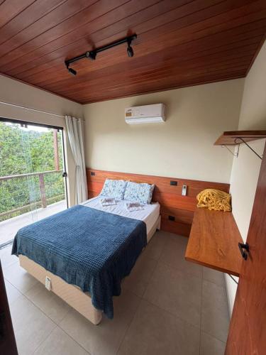 a bedroom with a bed with a blue blanket and a window at Estação Serra Negra in Bezerros