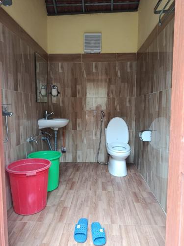 a bathroom with a toilet and a sink and two slippers at A Vũ Homestay & Coffee in Kon Cho Dri