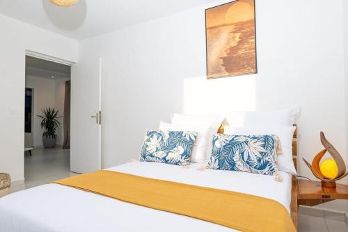 a bedroom with a bed with blue and white pillows at L' É'sens Karaïbes in Les Abymes