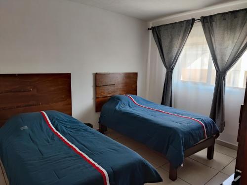 ein Schlafzimmer mit zwei Betten und einem Fenster in der Unterkunft Centro Queretaro Hospedaje Castillo in Casa Blanca La Corregidora