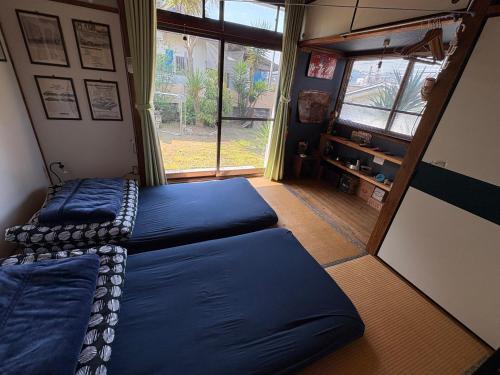 a bedroom with two beds and a large window at Norishicoauto Guesthouse in Chikushino