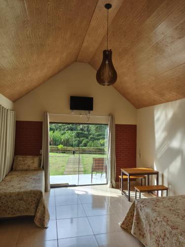 a bedroom with a bed and a window and a table at Chalés Pôr do Sol Alto Caparaó in Caparaó Velho